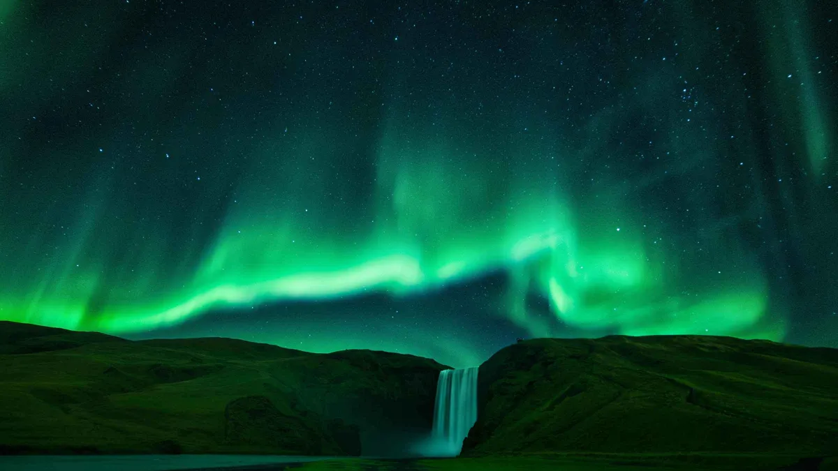 Coach tour group photographing the aurora on a south coast and northern lights tour reaching Vík, Iceland